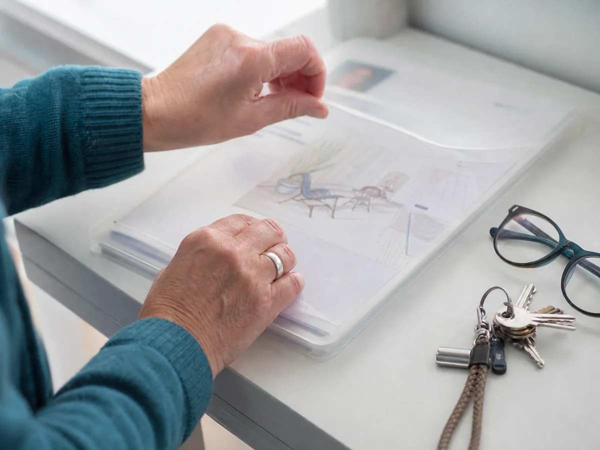 Hände packen Anschreiben und Ideenskizze in eine Mappe für das Gespräch bei der Arbeitsagentur