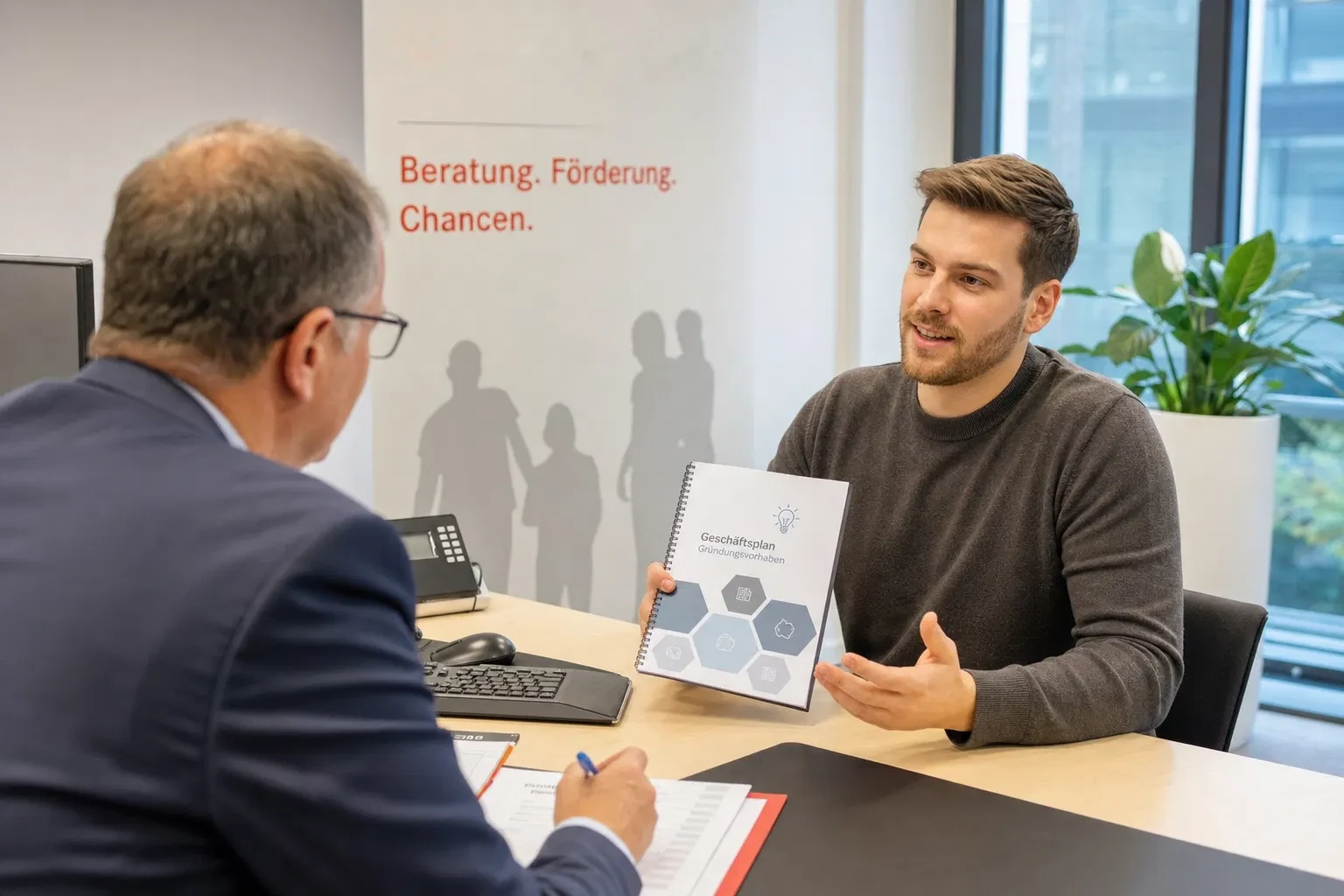 Junger Mann zeigt einem Berater am Schreibtisch eine gebundene Mappe mit der Aufschrift Geschäftsplan, der Berater macht sich Notizen