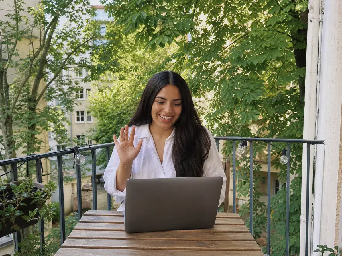 Junge Frau arbeitet auf ihrem Münchner Balkon per Videogespräch mit ihrem Gründungsberater