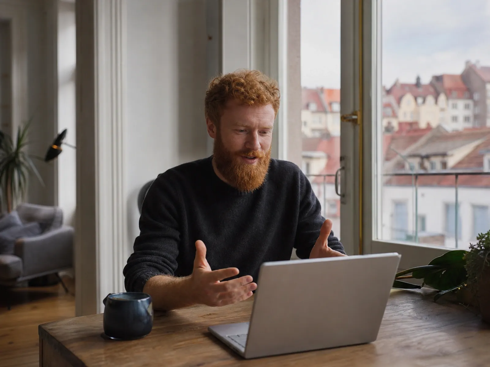 AVGS-Gründercoaching in Regensburg: Gründer im Videocall in seiner Altbauwohnung über den Dächern der Altstadt