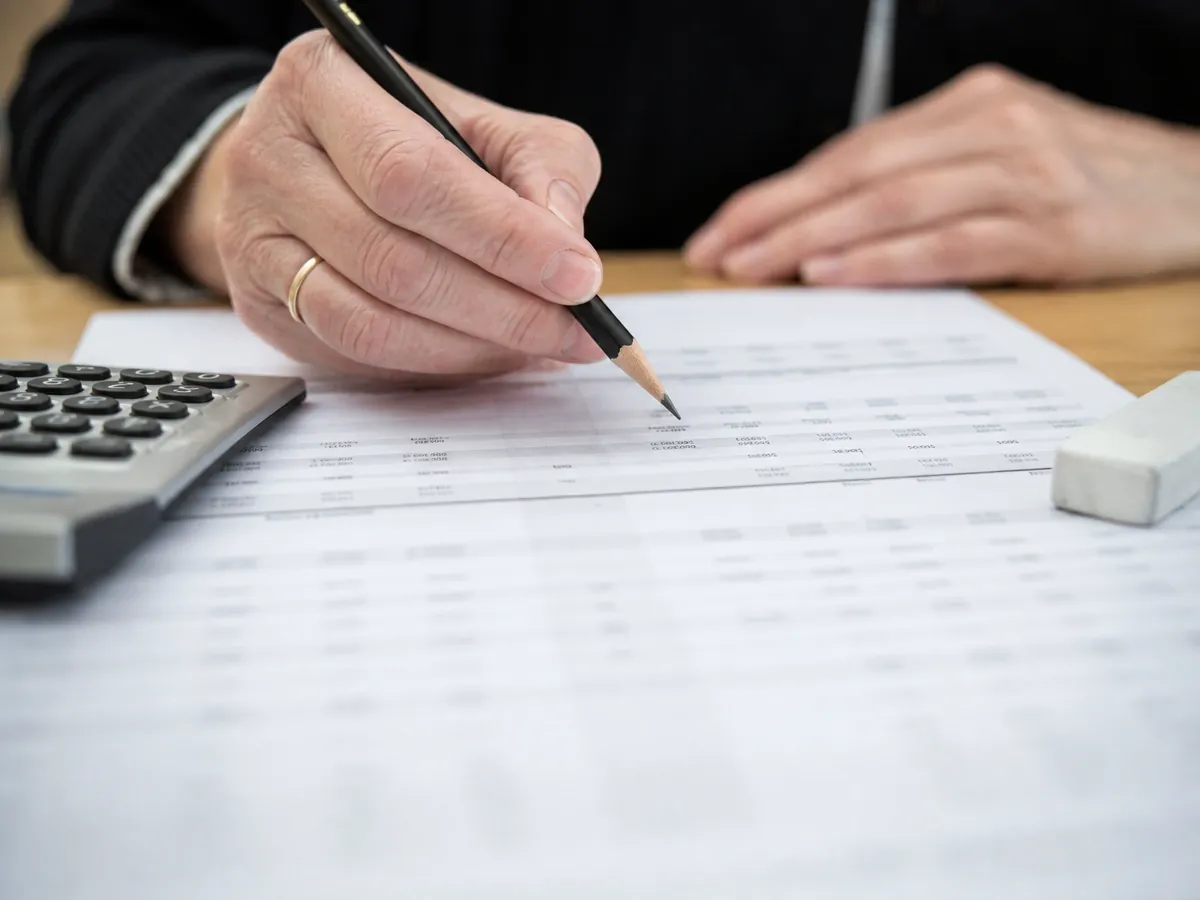 Hand bessert nach einer Absage der Bank den Finanzplan mit Bleistift nach