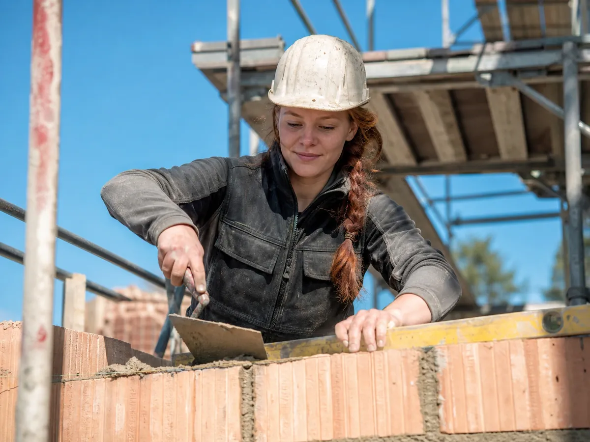 Maurermeisterin mauert auf der Baustelle, der Rohbau ist ein zulassungspflichtiges Handwerk