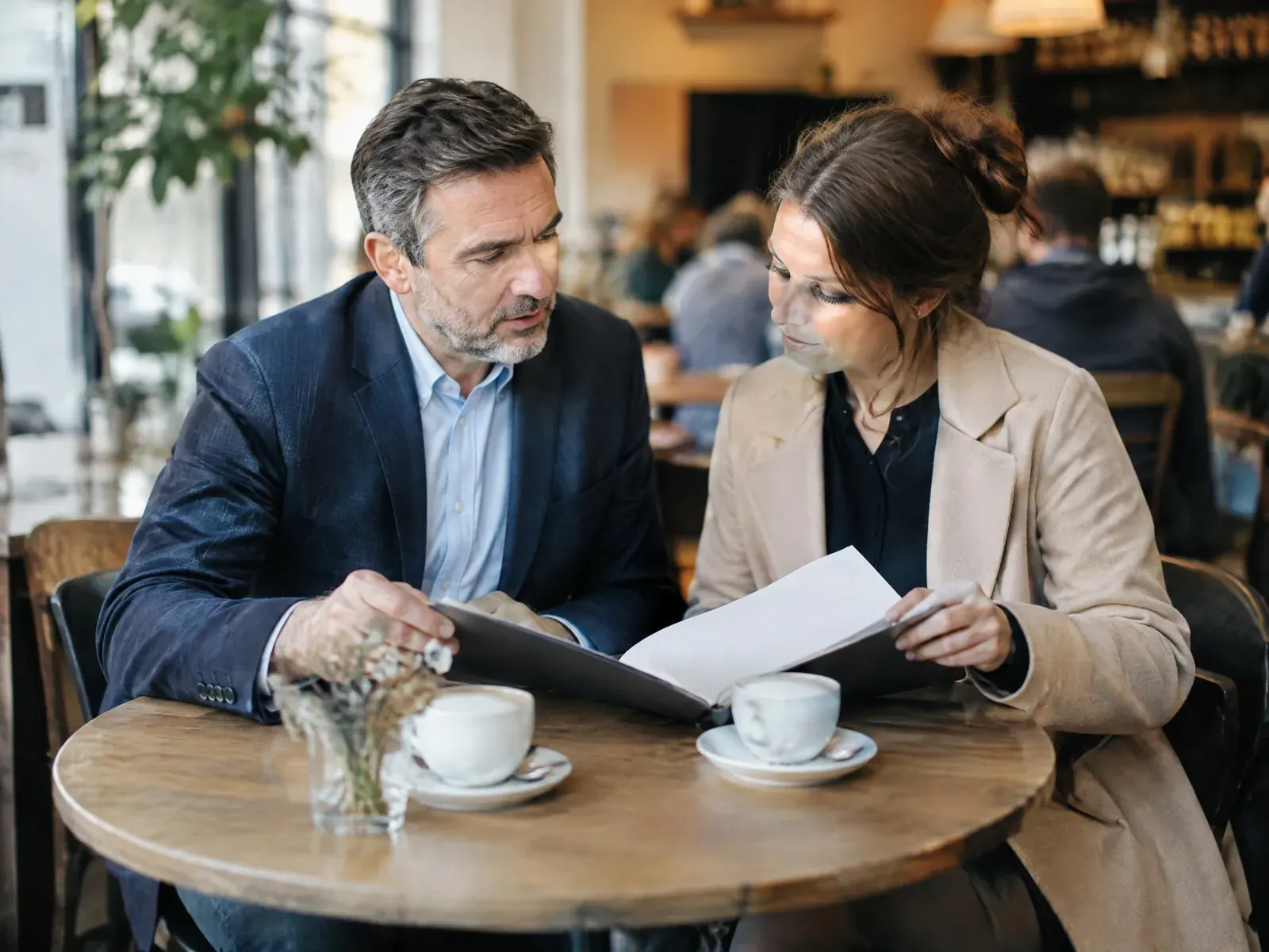 Café übernehmen: Käufer und Verkäuferin besprechen im Café die Unterlagen zur Übernahme