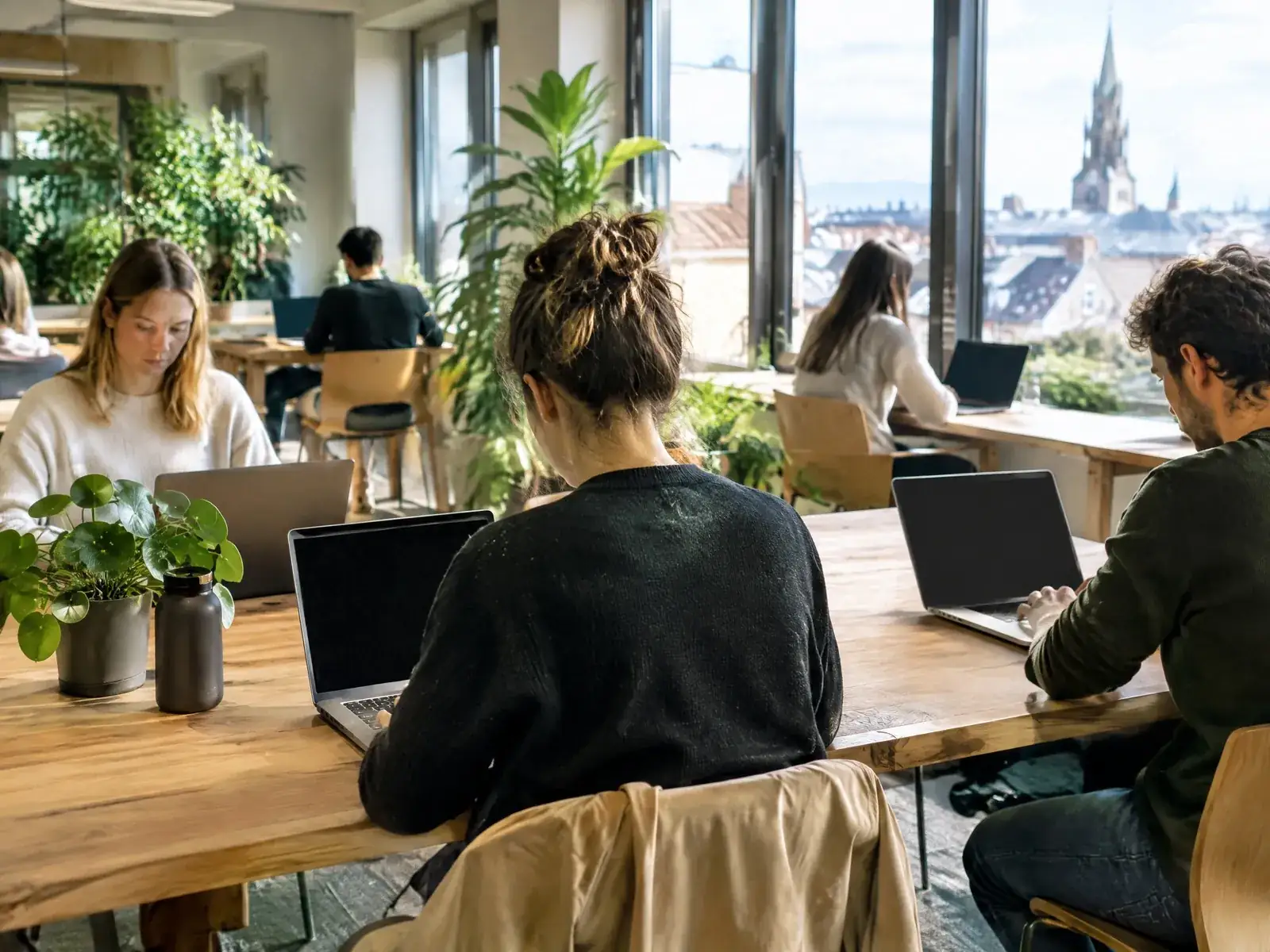 Coworking Space gründen: Menschen arbeiten an Holztischen in einem hellen Gemeinschaftsbüro