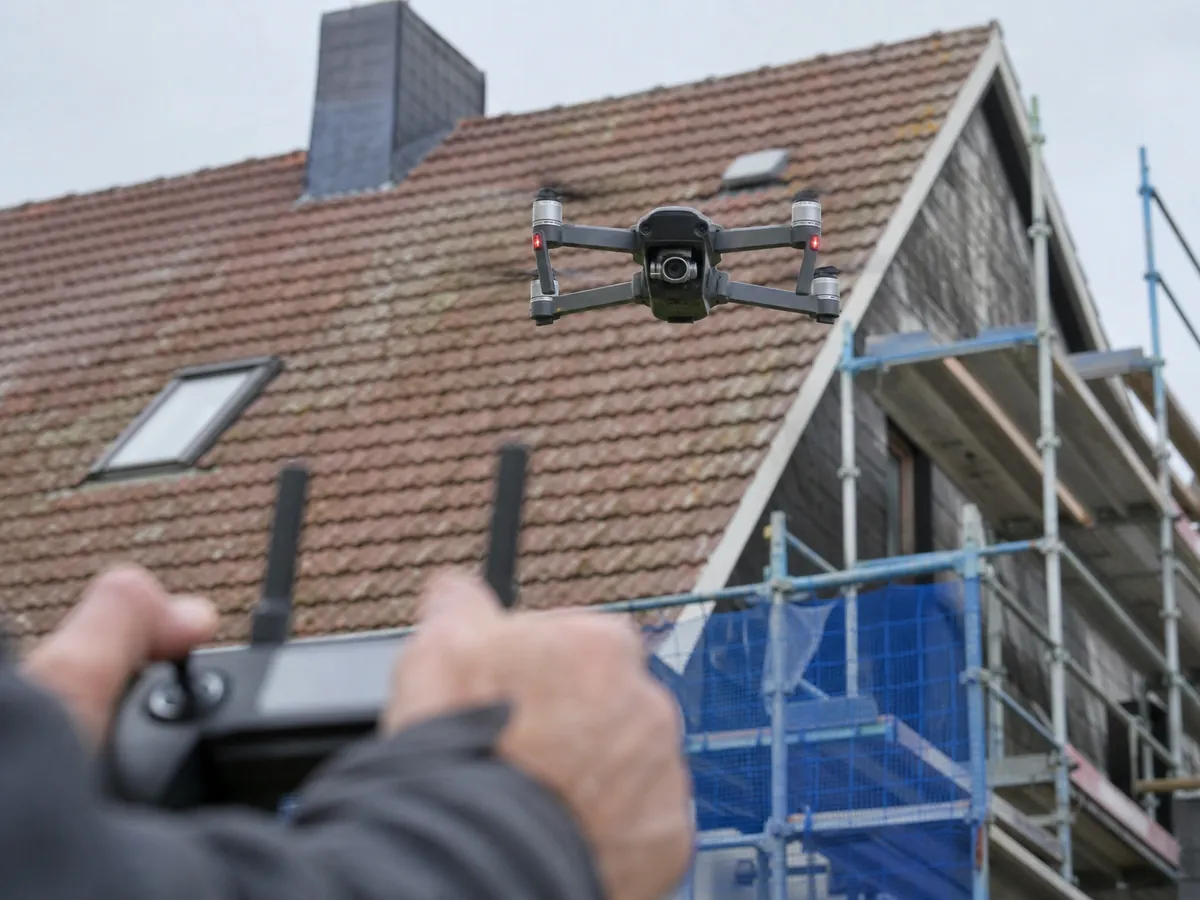 Drohne fliegt bei einem gewerblichen Einsatz zur Dachinspektion über ein Einfamilienhaus