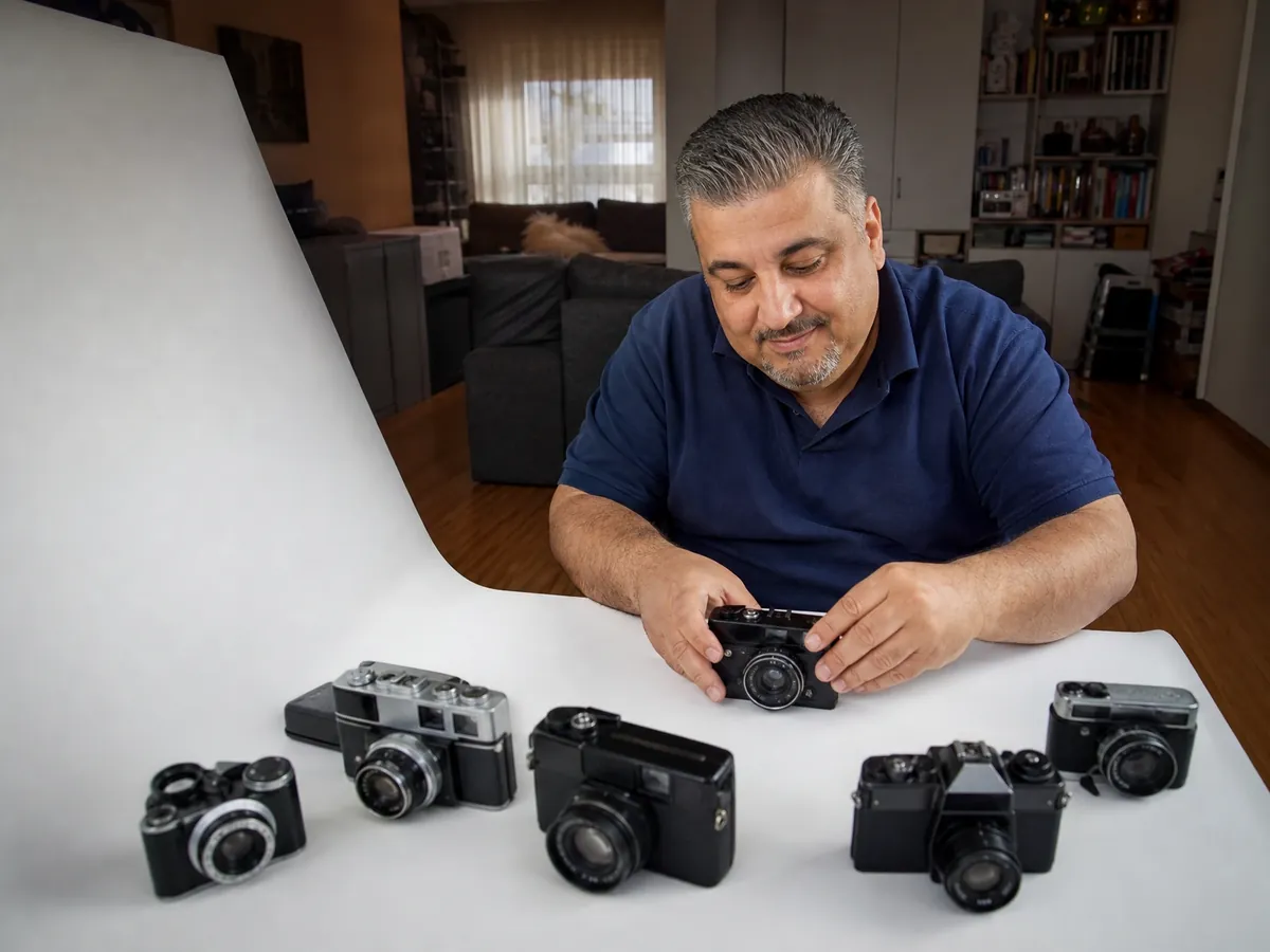 Verkäufer fotografiert im Wohnzimmer gebrauchte Vintage-Kameras für seine Onlineangebote