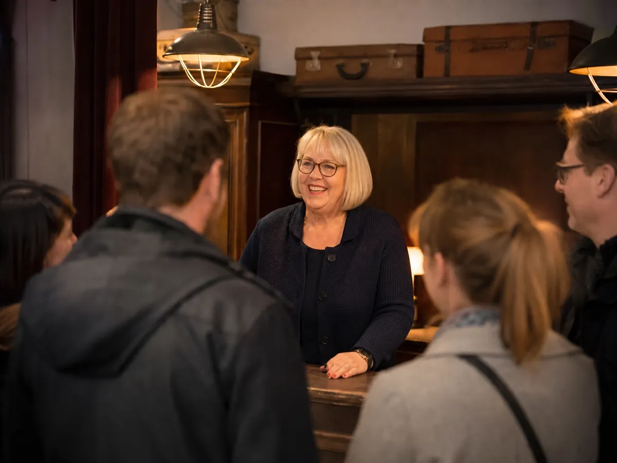 Betreiberin begrüßt eine Firmengruppe am Empfang ihres Escape Rooms zum gebuchten Teamevent