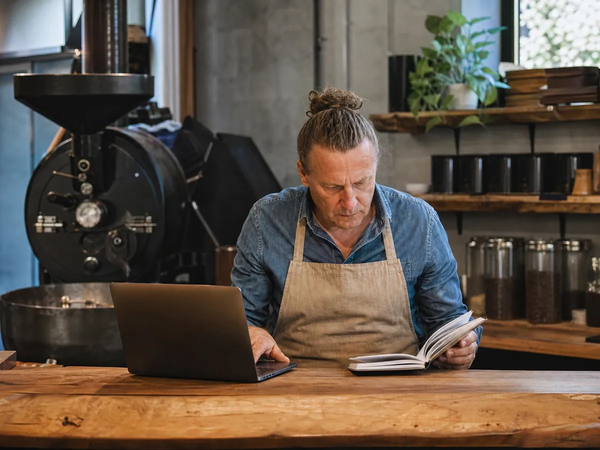 Gründer einer Kaffeerösterei recherchiert am Laptop, ob sein gewünschter Firmenname geschützt ist