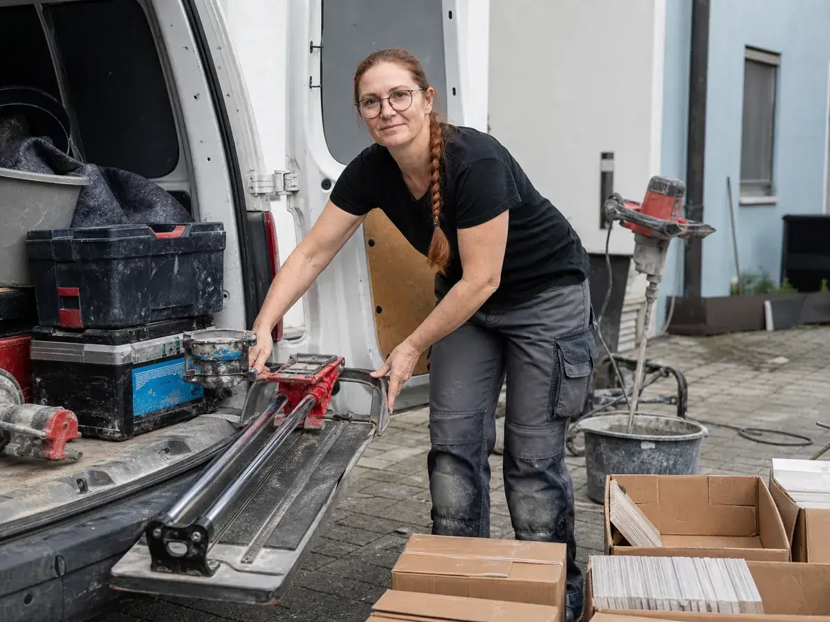 Fliesenlegerin belädt ihren Transporter – Fahrzeug und Werkzeug sind die größten Startkosten