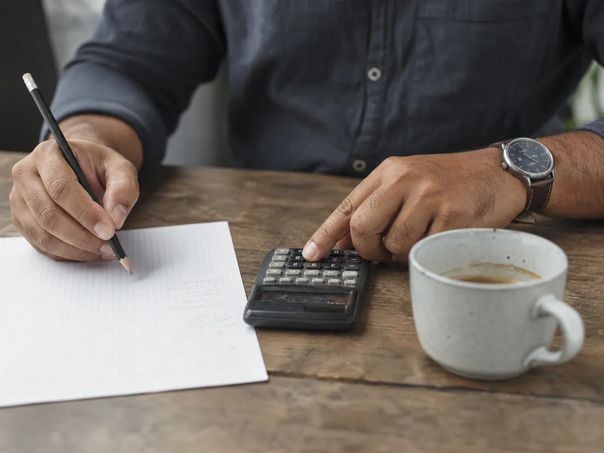 Hände schätzen mit dem Taschenrechner Umsatz und Gewinn für den Fragebogen beim Finanzamt