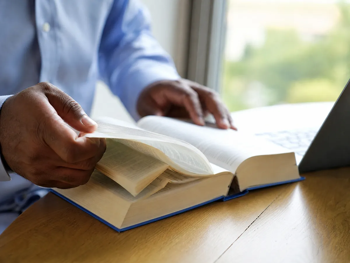 Freiberuflicher Übersetzer arbeitet mit Wörterbuch und Laptop – ohne Gewerbeanmeldung
