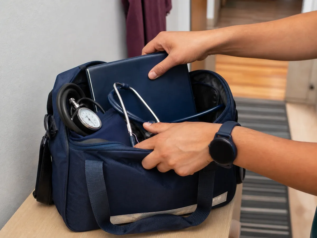Hände packen die Pflegetasche einer selbstständigen Pflegekraft vor dem nächsten Einsatz