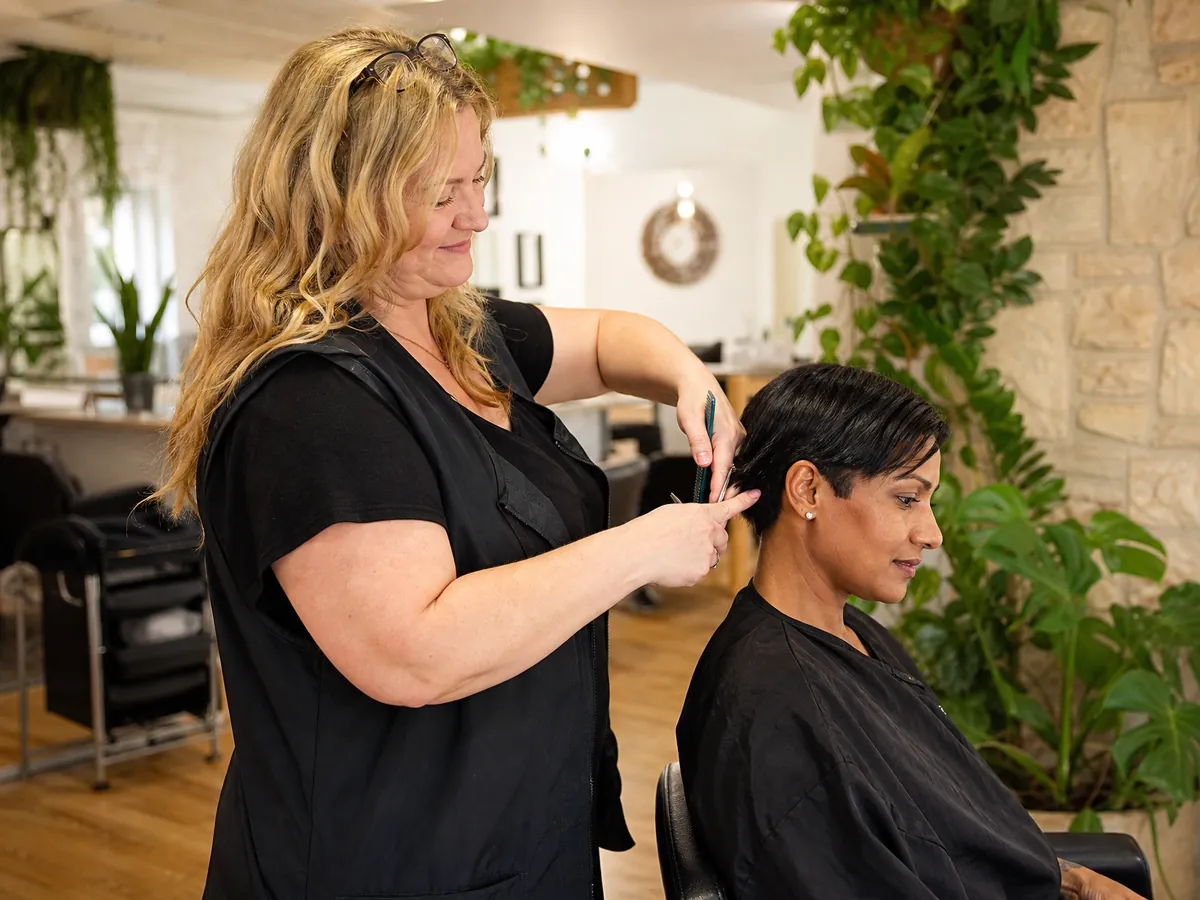 Friseurmeisterin schneidet einer Kundin im eigenen Salon die Haare
