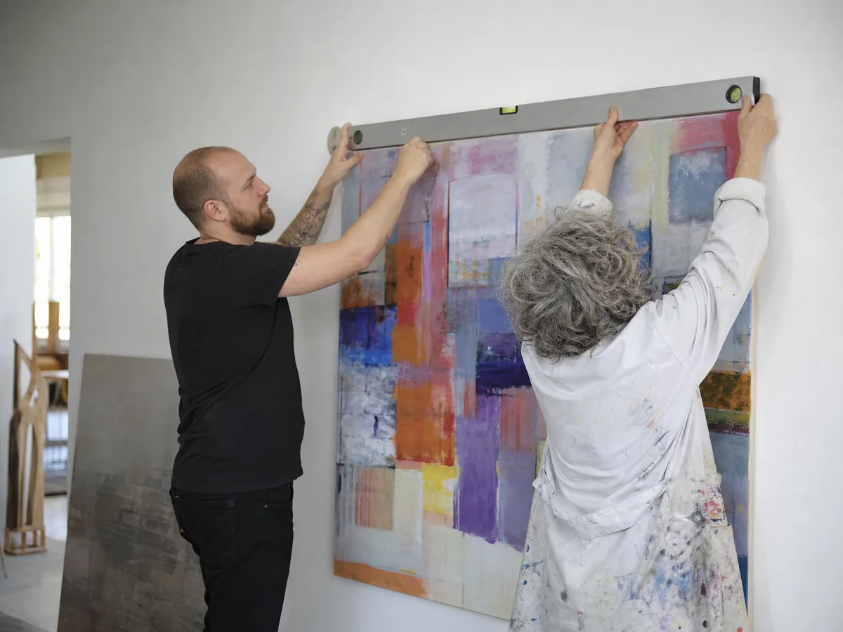 Galerist hängt mit einer Künstlerin ein Werk auf, das er in Kommission verkauft