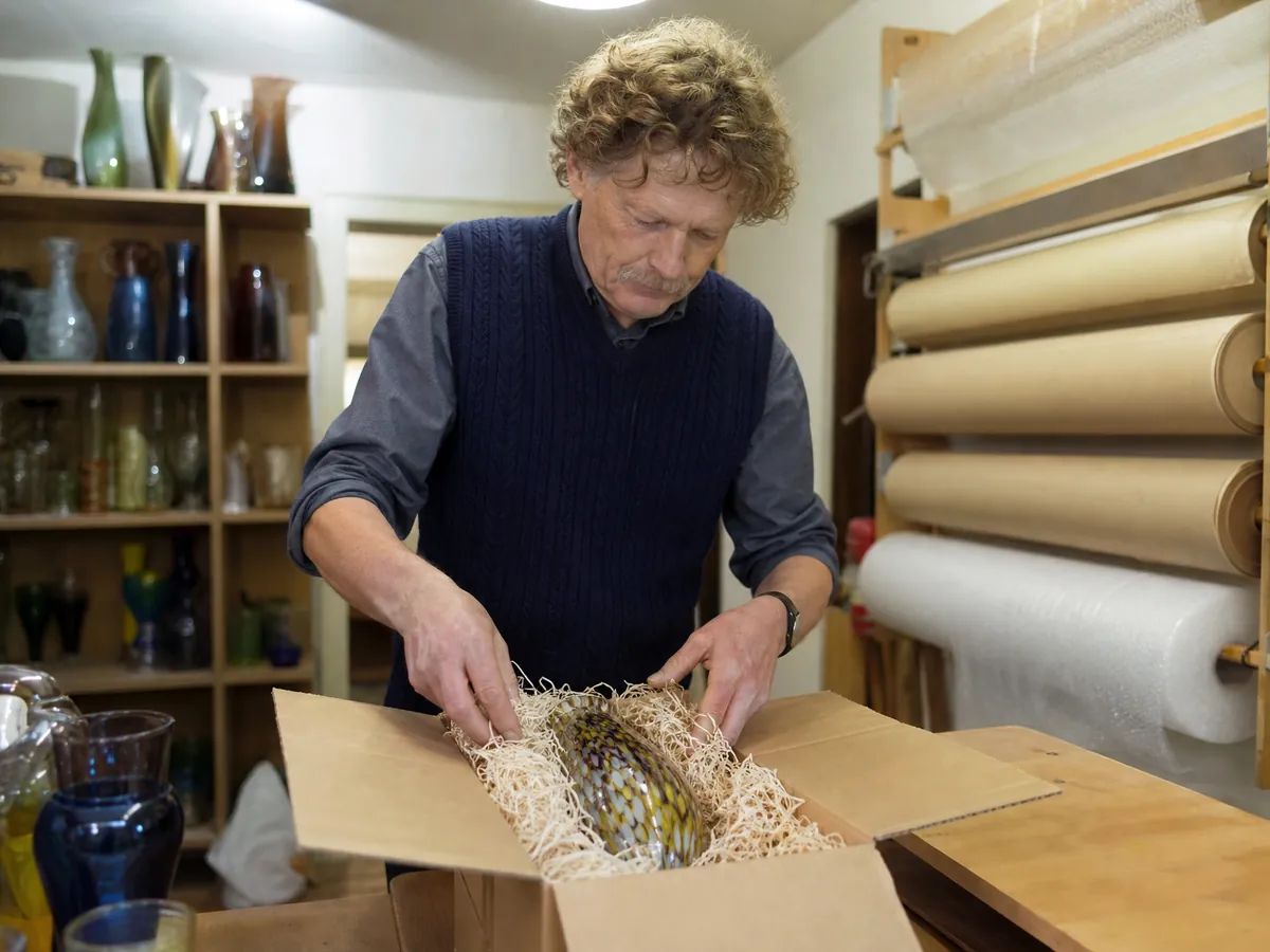 Inhaber verpackt eine Glasvase für den Versand aus dem Onlineshop seines Geschenkeladens