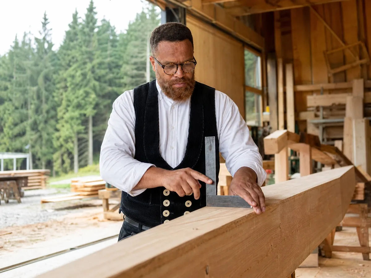 Zimmerermeister prüft einen Balken im Schwarzwälder Betrieb, den er mit Meisterprämie gründet