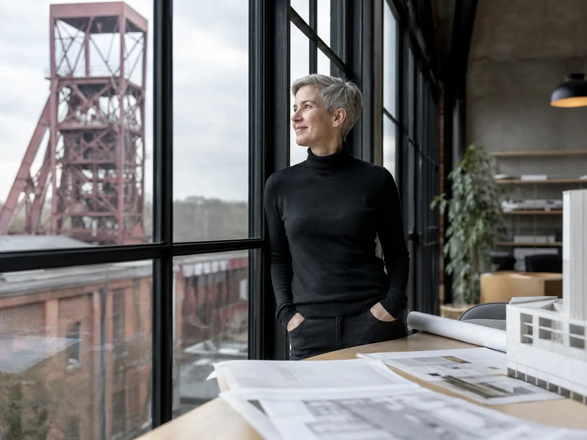 Gründerin in ihrem Büro in einem umgebauten Zechengebäude im Ruhrgebiet mit Blick aufs Fördergerüst