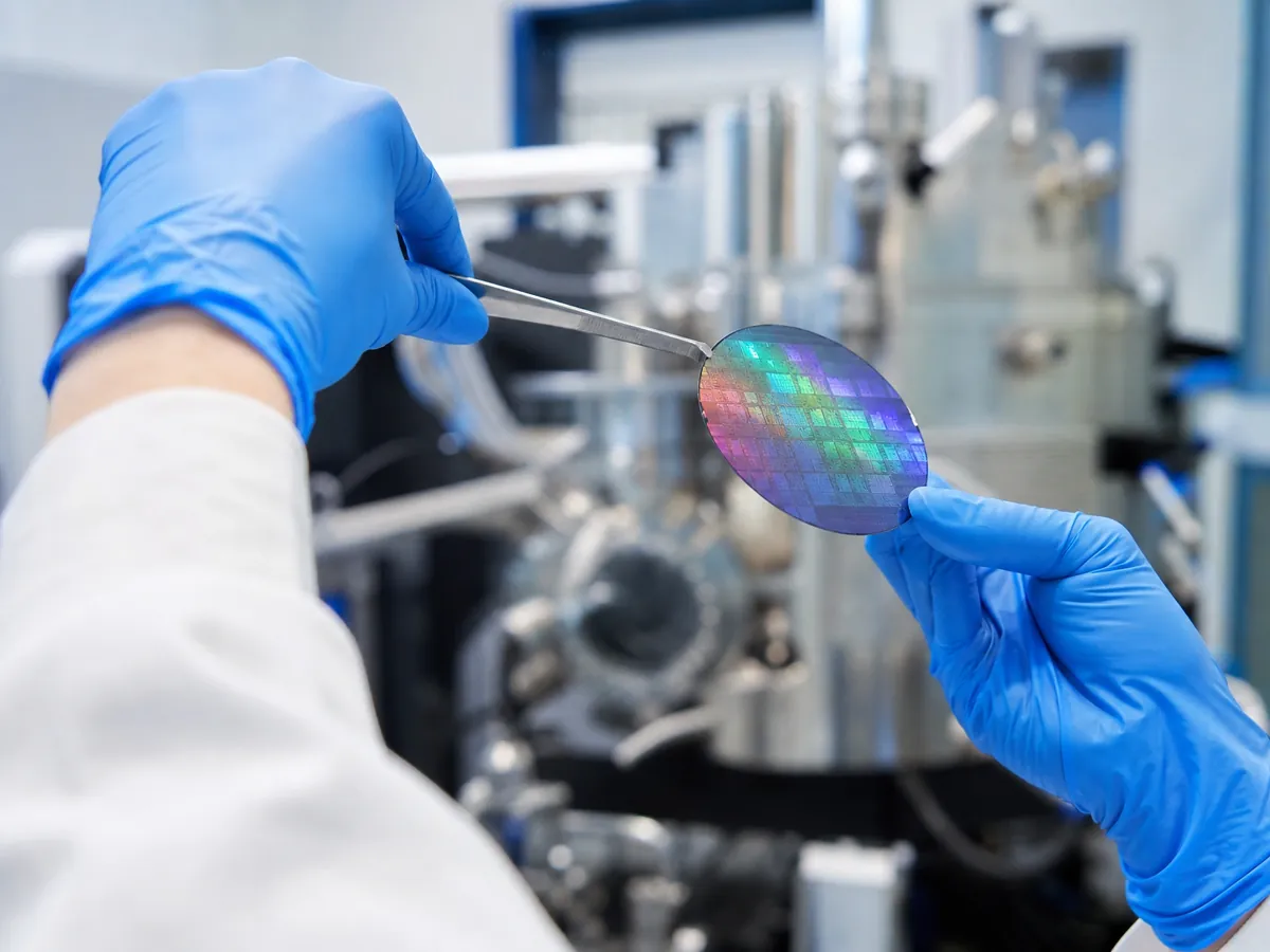 Hände prüfen in einem Dresdner Labor einen Wafer für eine Technologiegründung in Sachsen