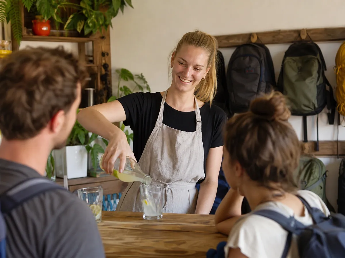 Gründerin bedient Gäste an der kleinen Bar im Gemeinschaftsraum ihres Hostels