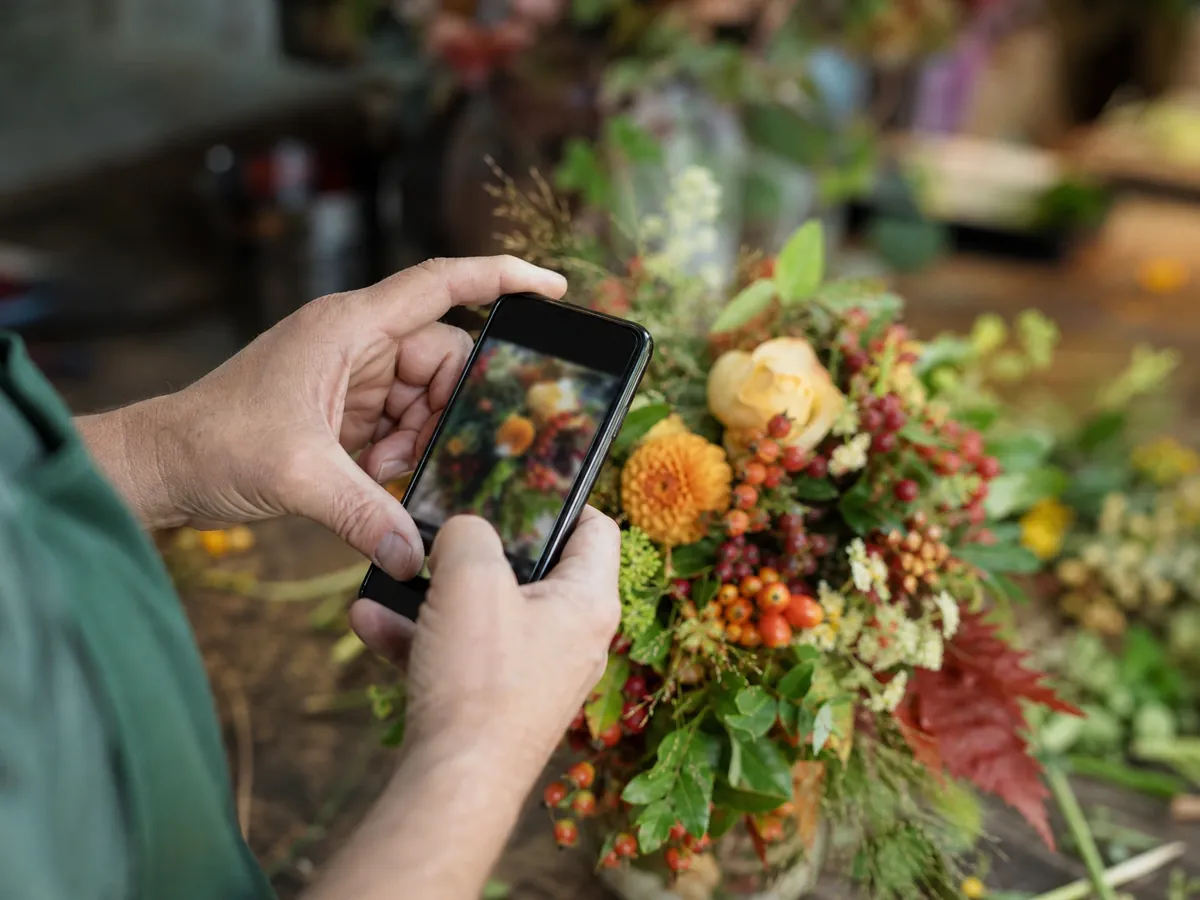 Florist fotografiert einen Blumenstrauß für das Social-Media-Profil seines Geschäfts