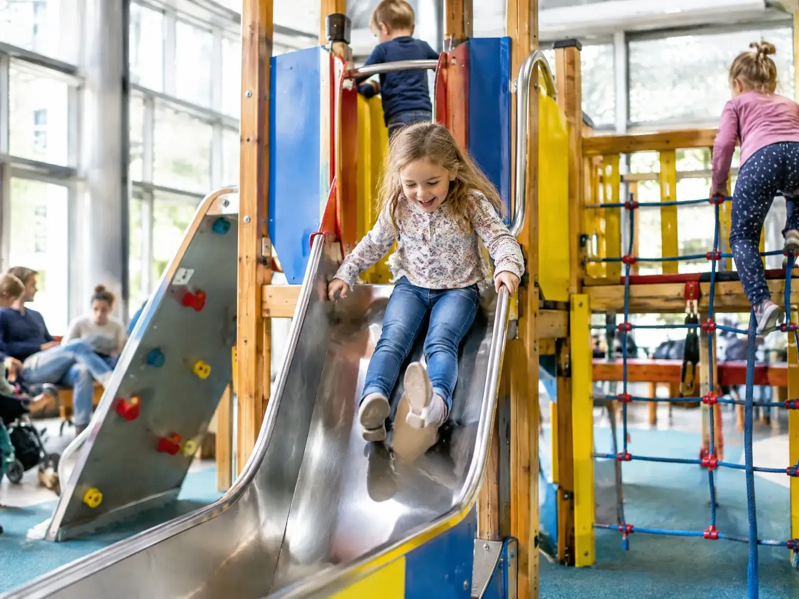 Indoorspielplatz eröffnen: Kinder rutschen und klettern in einer bunten Spiellandschaft