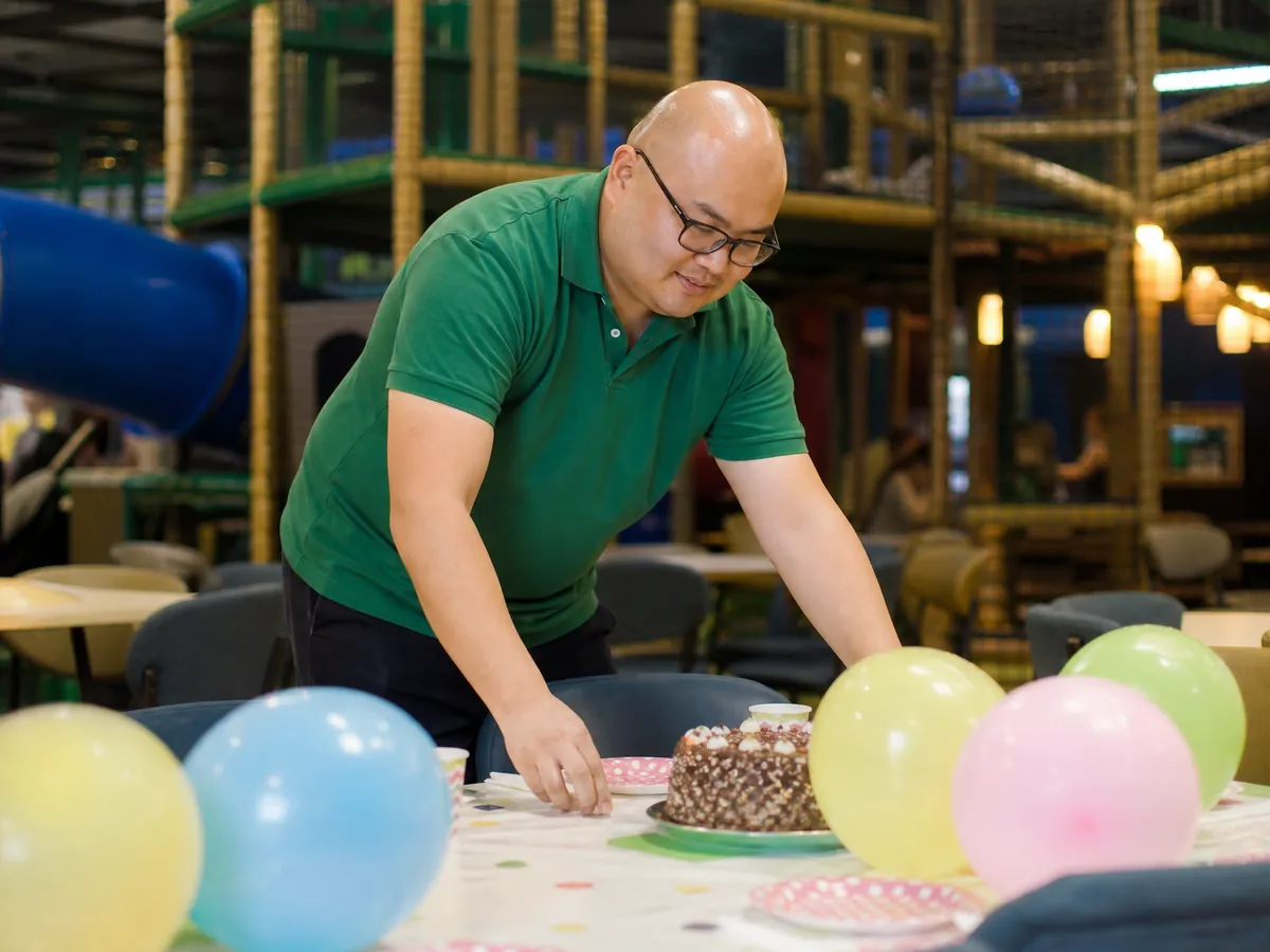 Betreiber deckt im Café seines Indoorspielplatzes einen Tisch für einen Kindergeburtstag