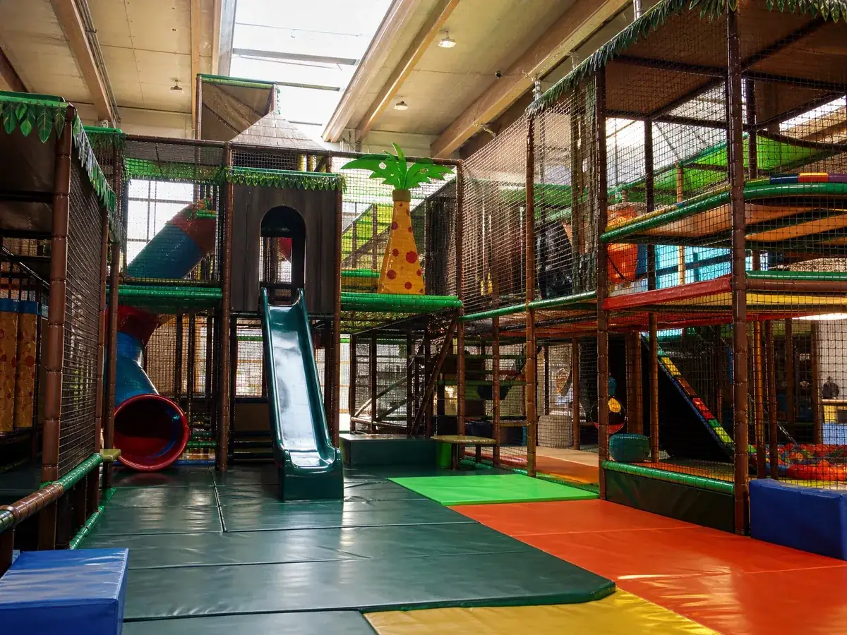 Leerer Indoorspielplatz mit Kletterlandschaft und Fallschutzmatten vor der Öffnung