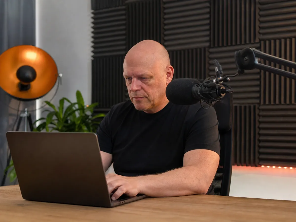 Content Creator arbeitet in seinem Homestudio am Laptop an seinem Profil
