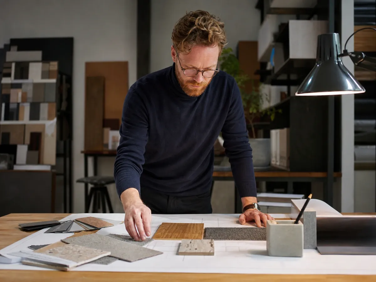 Innenarchitekt stellt in seinem Atelier Materialmuster auf einem Grundriss zusammen
