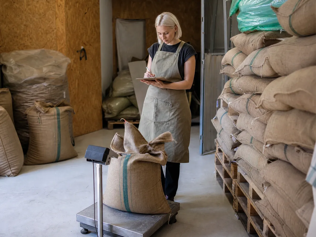 Rösterin wiegt im Steuerlager ihrer Kaffeerösterei Säcke mit Rohkaffee