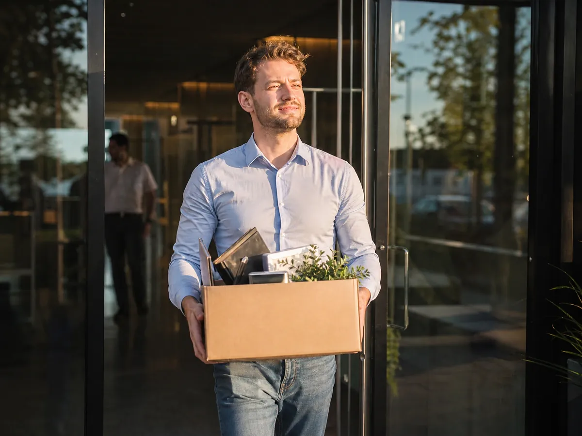 Junger Mann verlässt am letzten Arbeitstag das Büro für den Schritt in die Selbstständigkeit