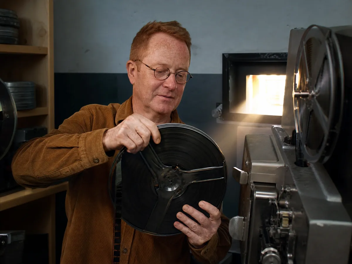 Ehrenamtlicher legt im Kommunalkino eine Filmrolle in den 35-mm-Projektor ein