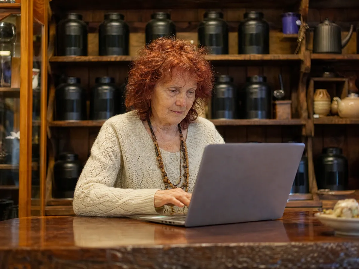 Gründerin recherchiert in ihrem Teeladen am Laptop, ob ihr gewünschter Markenname noch frei ist