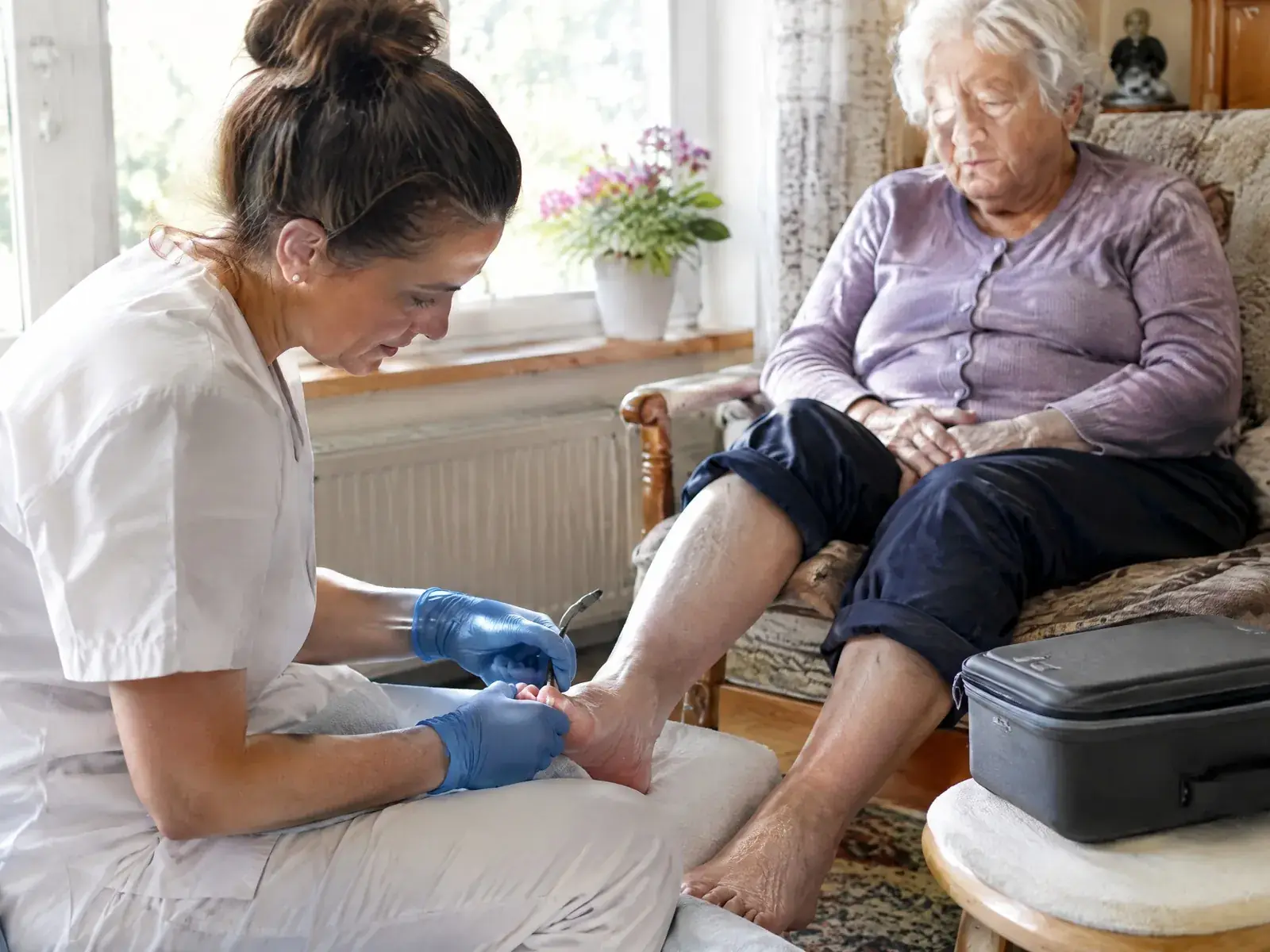 Mobile Fußpflege: Fußpflegerin behandelt eine Seniorin bei ihr zu Hause