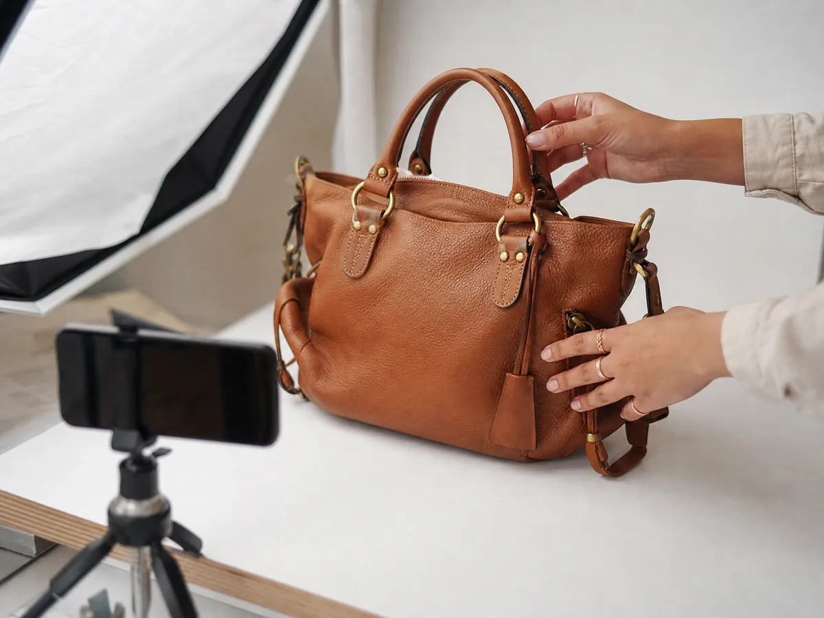 Hände richten eine Vintage-Handtasche für Produktfotos im Onlineshop eines Second-Hand-Ladens aus