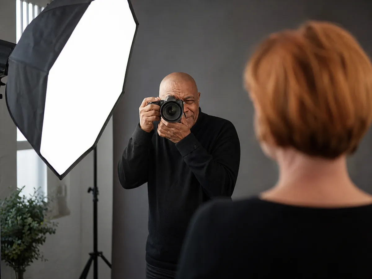 Selbstständiger Fotograf macht in seinem Studio ein Porträt einer Kundin mit Blitz und Softbox