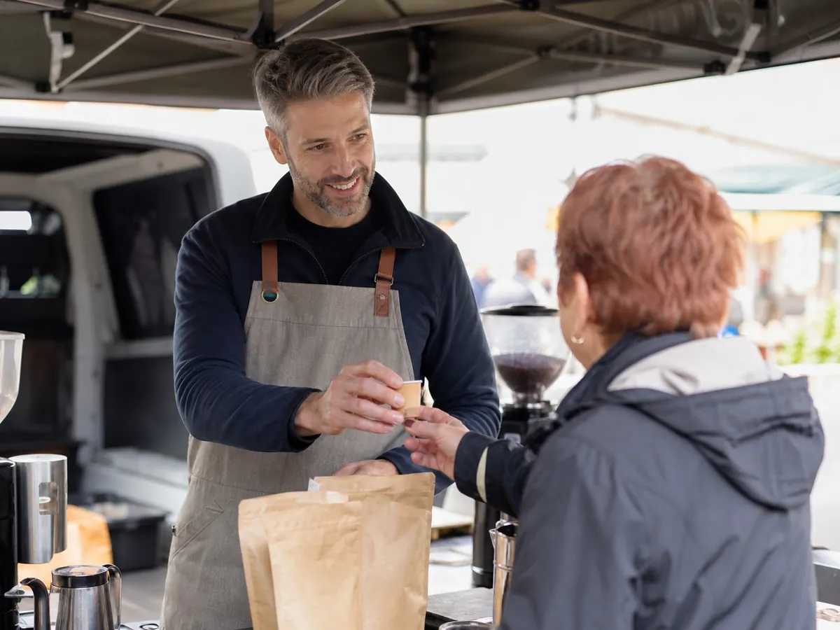 Gründer testet seine Geschäftsidee mit selbst geröstetem Kaffee an einem Probestand auf dem Wochenmarkt
