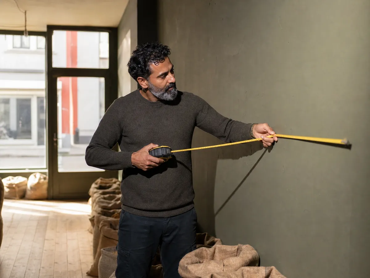 Gründer mit Migrationshintergrund misst das Ladenlokal für sein Gewürz- und Feinkostgeschäft aus