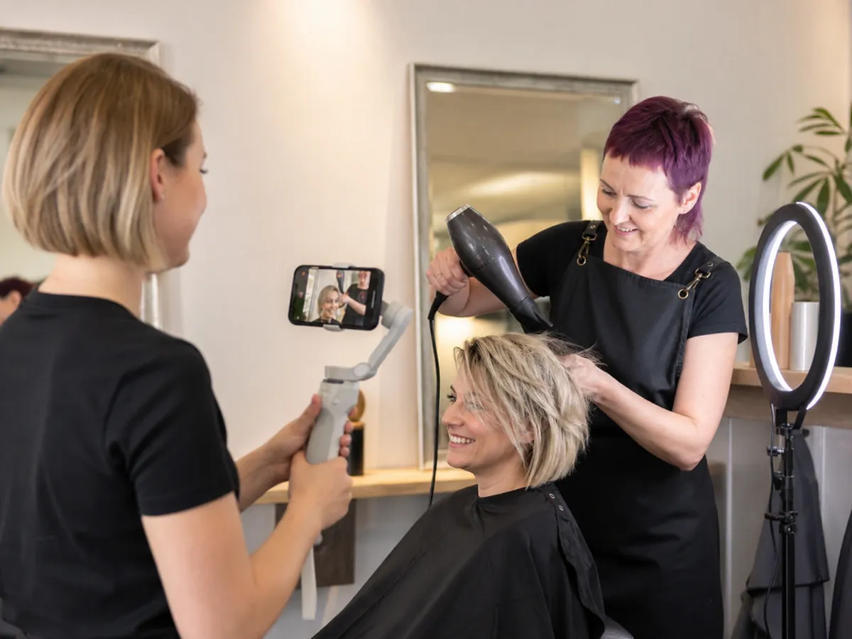 Social-Media-Managerin filmt in einem Friseursalon Inhalte für ihre auf Friseure spezialisierte Agentur