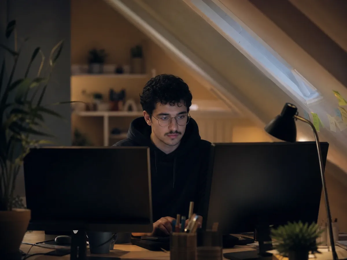 Junger Entwickler arbeitet abends in seiner Dachkammer am Aufbau seiner eigenen Softwarefirma