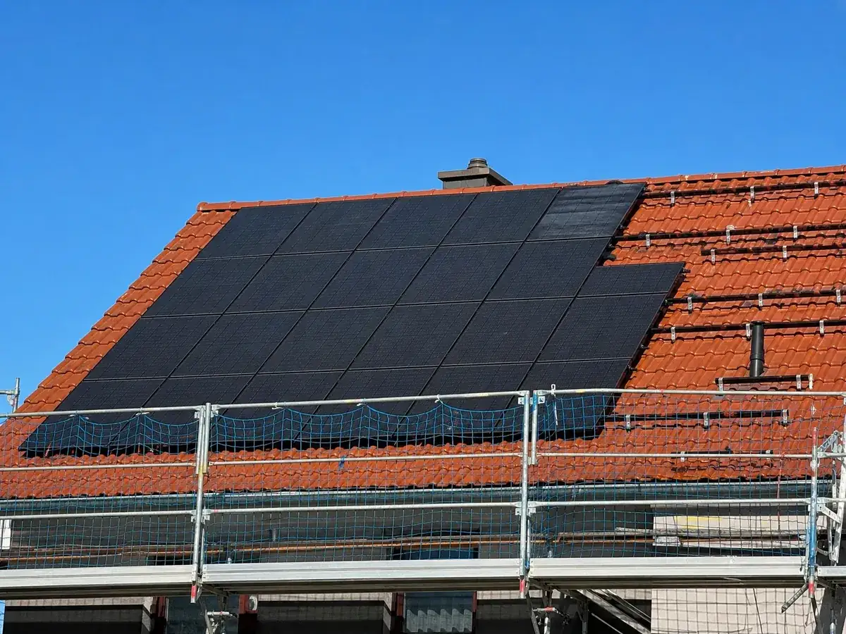 Photovoltaikmodule auf einem Ziegeldach mit Gerüst, Arbeiten, die das Dachdeckerhandwerk betreffen