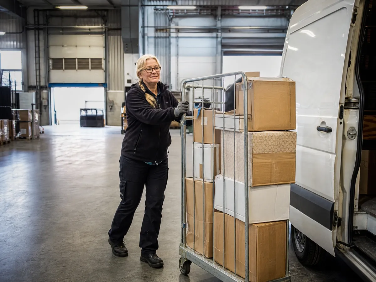 Unternehmerin belädt im Paketdepot frühmorgens ihren Transporter für die Zustelltour als Subunternehmerin