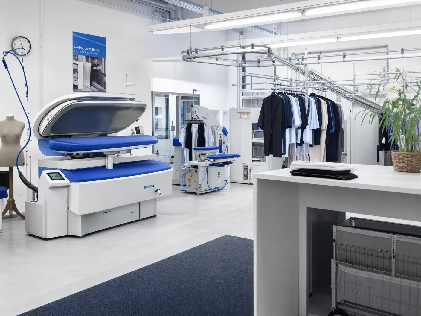 Heller Reinigungsbetrieb mit blauer Bügelpresse, Hemdenpuppe und Kleiderstangen voller gereinigter Kleidung