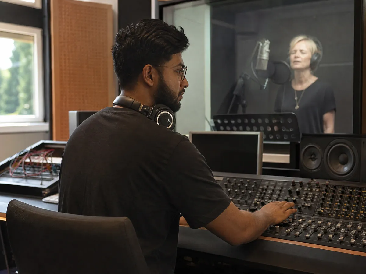 Tontechniker nimmt im Regieraum eines Tonstudios eine Sängerin auf, an deren Darbietung Rechte entstehen