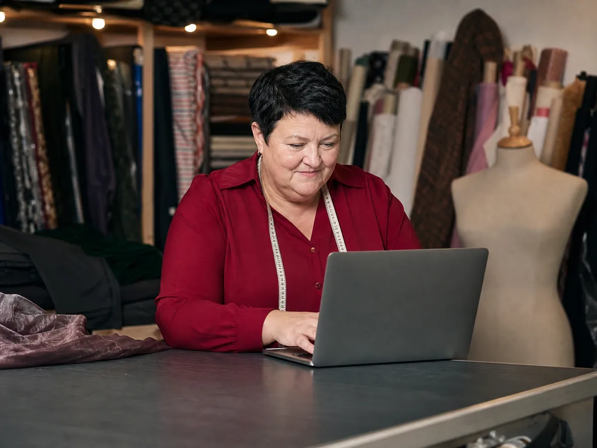 Schneiderin übermittelt nach Ladenschluss am Laptop ihre Umsatzsteuervoranmeldung über ELSTER