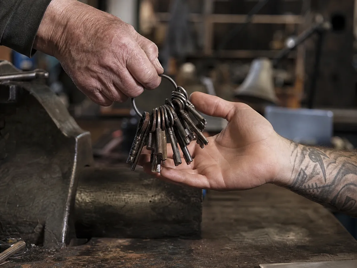 Ältere Hand übergibt einer jüngeren den Schlüsselbund eines Handwerksbetriebs bei der Nachfolge