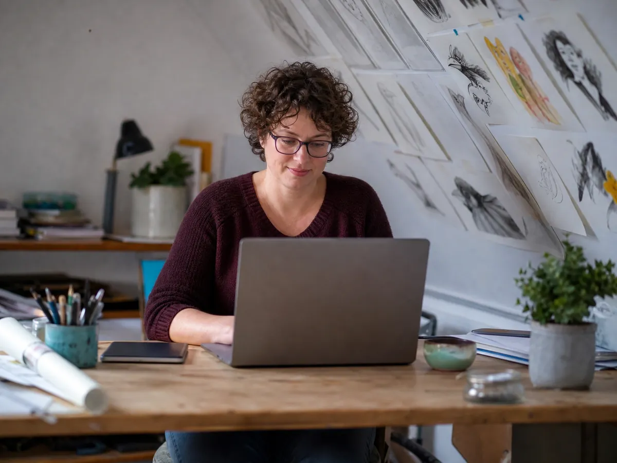 Grafikdesignerin erledigt am Laptop die steuerliche Erfassung als Voraussetzung für die USt-IdNr.