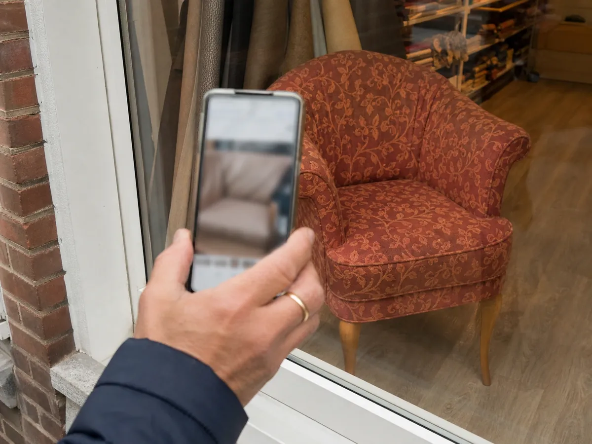 Smartphone vor dem Schaufenster einer Polsterei, die über ihre Website bei Google gefunden werden will